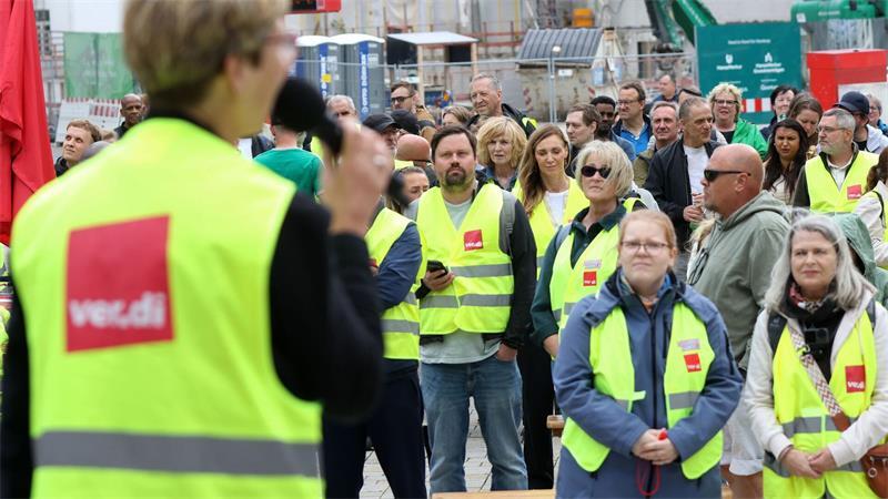 Teilnehmer der Kundgebung hören einer Rednerin zu.