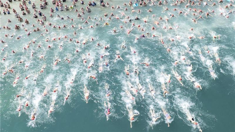 Bilder des Tages Teilnehmer der „Stadtzürcher Seeüberquerung“ stürzen sich in Zürich bei hochsommerlichen Temperaturen in den Zürichsee.