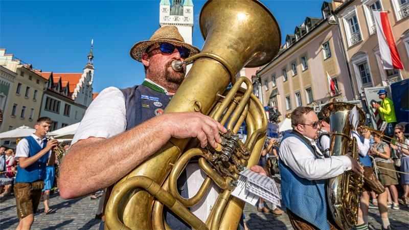 Teilnehmer des traditionellen Auszugs zum Gäubodenvolksfest gehen in Tracht und mit Blasinstrumenten durch die Innenstadt von Straubing.