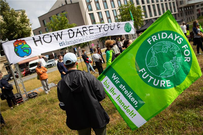 Teilnehmer einer Aktion der Klimabewegung «Fridays For Future» stehen mit einem Banner auf einer Wiese vor der Hamburger SPD-Zentrale. Foto: Christian Charisius/dpa