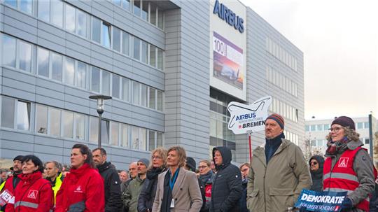 Teilnehmer einer Demonstration der IG Metall Bremen stehen vor dem Airbus Werk in Bremen.