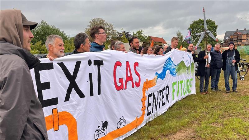 Teilnehmer halten ein Protestbanner bei der „Exit Gas - Enter Future“-Fahrradprotesttour auf dem Hof von Claus Blohm in ihren Händen.