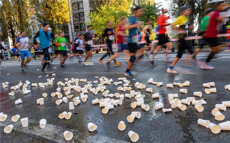 Holzmedaillen, weniger Müll: Marathons wollen nachhaltig sein Teilnehmer laufen an leeren Bechern vorbei, die neben einer Wasserversorgungsstation am Rand der Strecke auf der Straße liegen. Die großen deutschen Stadt-Marathons verstärken ihr Engagement für die Umwelt. Foto: Peter Kneffel/dpa