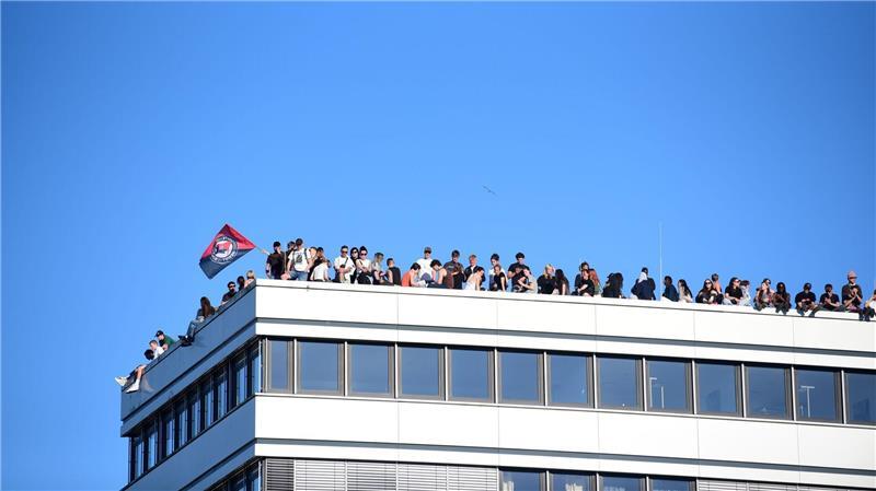 Teilnehmer stehen bei einer Demonstration mit dem Motto „Krieg und Krise haben System. Als Klasse vereint: Sozialismus erkämpfen!“ auf dem Dach eines Hauses in Hamburg.