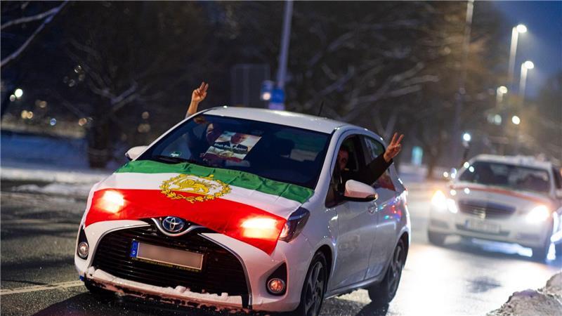 Teilnehmer zeigen Peace-Zeichen. In der Windschutzscheibe ist ein Foto von Reza Pahlavi zu sehen, dem Sohn des 1979 gestürzten Schahs.