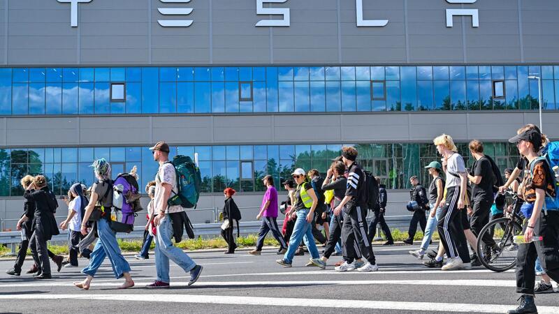 Protest gegen Tesla dürfte nach Aktionswoche weitergehen Teilnehmerinnen und Teilnehmer eines Protestmarschs laufen am Tesla-Werk vorbei.