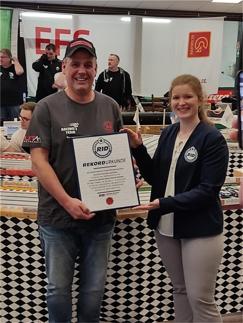 Apenser stellen überraschend neuen Slotcar-Weltrekord auf Thomas Hartmann erhält von Laura Kuchenbecker die Urkunde vom Rekordinstitut für Deutschland.