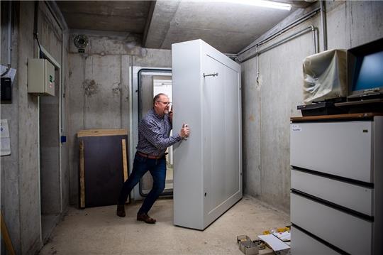 Thomas Otto, Bürgermeister der Gemeinde Saterland, stemmt eine schwere Tür zu den entwidmeten Schutzräumen im Keller des Rathauses auf. Foto: Sina Schuldt/dpa
