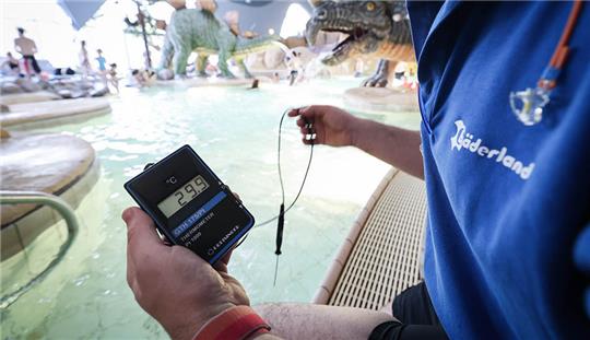 Thor Ruiz, stellvertretender Badleiter im „Festland“ Hallenbad Bäderland, prüft mit einem Digitalthermometer die Wassertemperatur im Planschbecken. Die als Energie-Sparmaßnahme im Hamburger Bäderland um ein Grad gesenkte Wassertemperatur soll an allen Standorten vorerst beibehalten werden. Foto: Christian Charisius/dpa