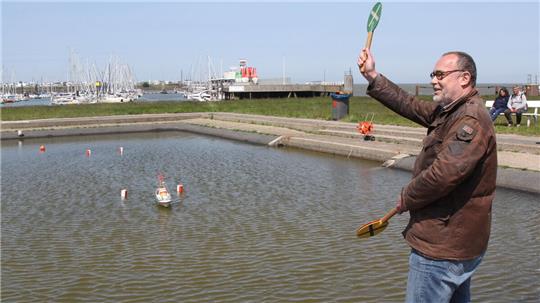 Thore Schulz, Vorsitzender des Schiffsmodellbauclubs Cuxhaven, hebt die grüne Kelle: Ohne Bojenberührung ist der kleine Seenotrettungskreuzer durch Tor gekommen. Foto: Reese-Winne