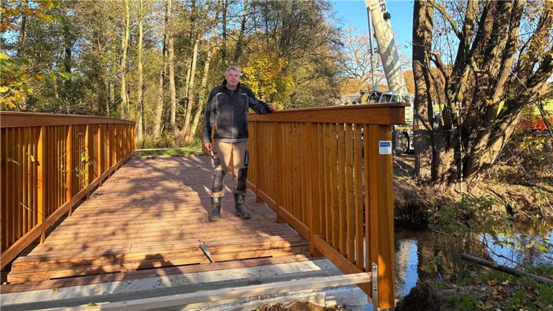 Millimeterarbeit am Kran: Neue Holzbrücke schwebt über die Aue Timo Bremmer von der Firma Holzbau Busmann ist einer der Ersten, der die neue Brücke betreten hat.