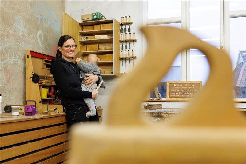 Tischlerin kämpft für Mutterschutz bei Selbstständigen Tischlermeisterin Johanna Röh steht mit ihrem Kind auf dem Arm in der Werkstatt ihres Betriebes. Die Mutter und Tischlermeisterin hat eine Petition zur Reform des Mutterschutzes auf den Weg gebracht. Foto: picture alliance/dpa | Friso Gentsch