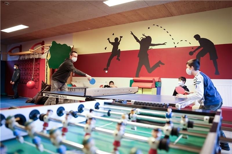 Tobias Lucht spielt Tischtennis mit drei Jungen im Sportraum des Kinderprojekts. Foto: Charisius/ dpa