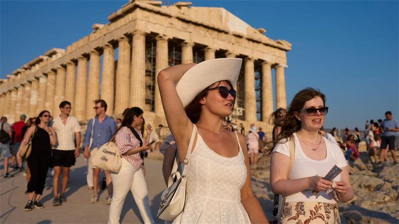 Touristen gehen an einem heißen Tag am antiken Parthenon-Tempel auf dem Akropolis-Hügel vorbei.