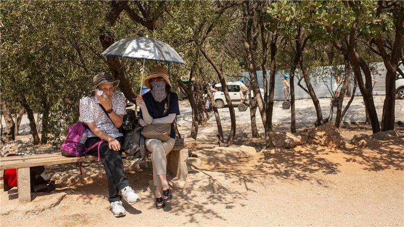 Gesundheitsrisiko Klimawandel: WHO-Gremium soll Hilfe bieten Touristen sitzen unter Bäumen am Eingang der Akropolis in Athen.