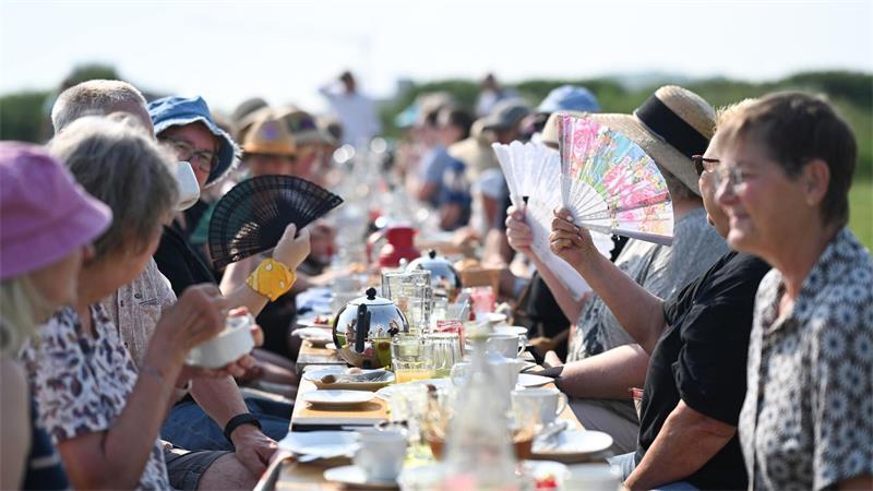 Touristen und Einheimische frühstücken gemeinsam am Deich.