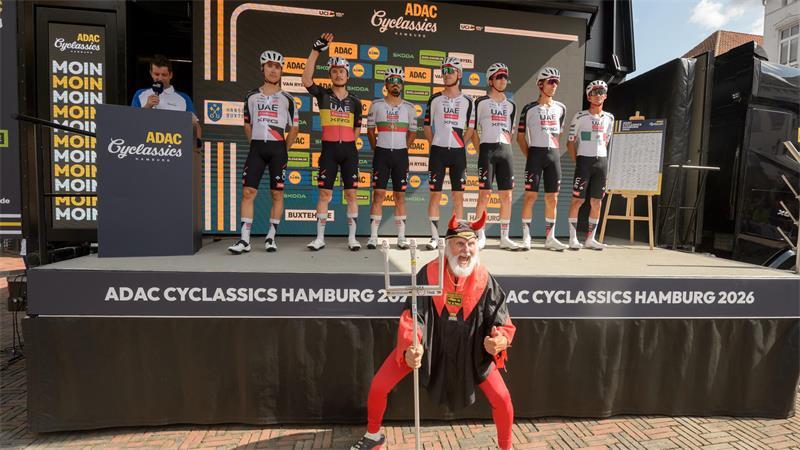 In Buxtehude ist der Teufel los - Super-Star del Toro begeistert Fans „Tourteufel“ Didi Senft in seiner typischen Pose. Hinter ihm das Team UAE-Emirates um Shootingstar Isaac del Toro (rechts).