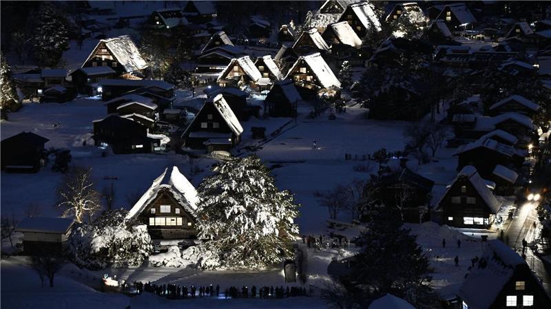 Traditionelle Strohdachhäuser sind mit Schnee bedeckt und werden im zum Weltkulturerbe gehörenden Dorf Shirakawa-go in der Präfektur Gifu in Zentraljapan beleuchtet.