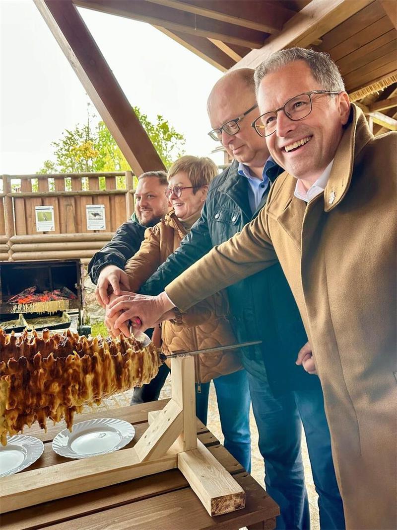 Delegation aus Stade besucht die Partner in Goldap Traditioneller polnischer Baumkuchen wird überm Feuer angeschnitten.