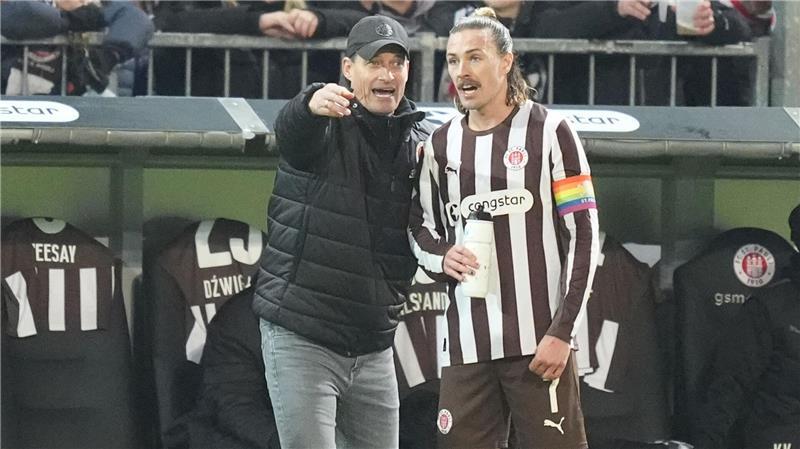Trainer Alexander Blessin spricht mit St.-Pauli-Kapitän Jackson Irvine.
