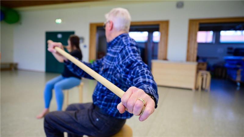 Trainiert werden unter anderem das Aufstehen vom Stuhl ohne Armunterstützung, der Stand auf einem Bein oder die Oberkörper-Flexibilität mit Stäben im Sitzen.