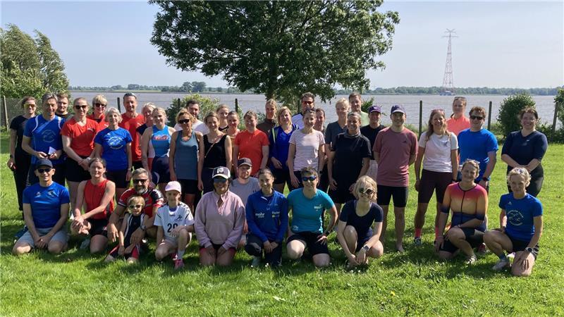 Premiere: 580 Triathleten schwimmen, radeln und laufen im Alten Land 40 Sportler des Team Buxtehude stehen und sitzen für ein Gruppenbild auf dem Rasen im Freibad Hollern-Twielenfleth.