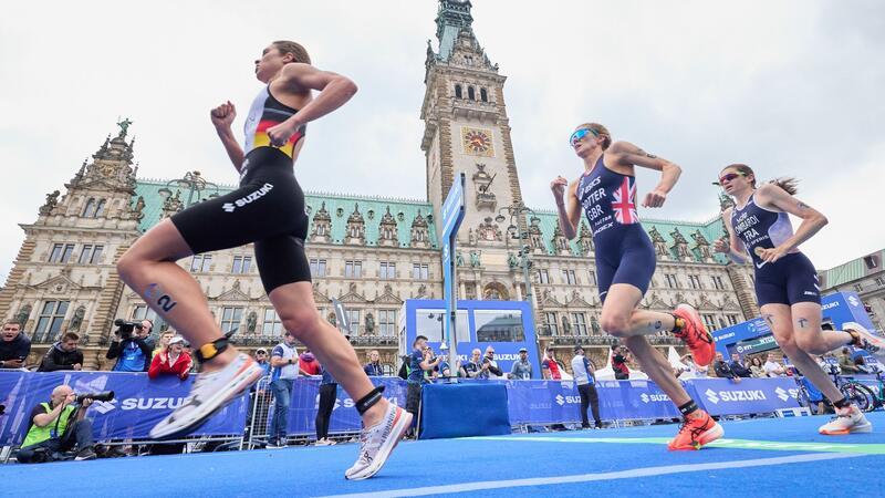 Triathlon-Teilnehmerinnen laufen am Hamburger Rathaus vorbei.