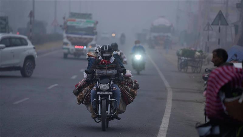 Trübe Sicht: Ein Händler transportiert seine Ware per Motorrad und fährt damit durch dichten Nebel im indischen Jammu. 