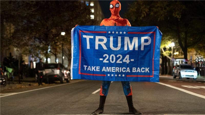 Trump-Unterstützer im Spider-Man-Kostüm mit einem Trump-Transparent am Tag der US-Präsidentschaftswahl 2024 in Washington.