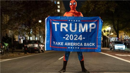 Trump-Unterstützer im Spider-Man-Kostüm mit einem Trump-Transparent am Tag der US-Präsidentschaftswahl 2024 in Washington.