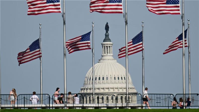 US-Fahnen wegen am Washington Monument. Im Hintergrund ist die Kuppel des US-Kapitols zu sehen.