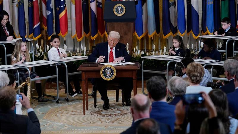 US-Präsident Donald Trump unterzeichnet umgeben von Kindern eine Anordnung im East Room des Weißen Hauses.
