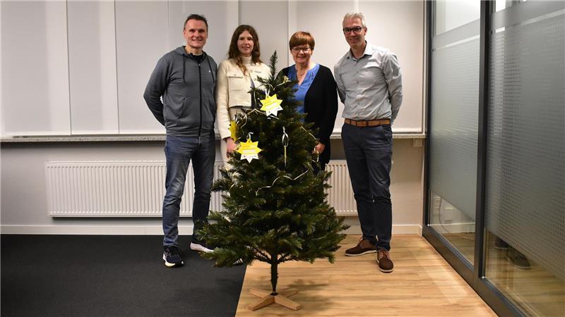 Udo Feindt, Beke zum Felde, Beatrice Konsulva und Claus Gerkens stehen in der Volksbank-Filiale in Jork vor einem Weihnachtsbaum mit gelben Sternen.