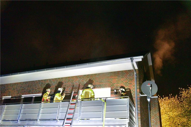Über den Balkon auf der Gebäuderückseite verschaffen sich die Einsatzkräfte Zutritt. Derweil steigt Rauch auf. Foto Beneke