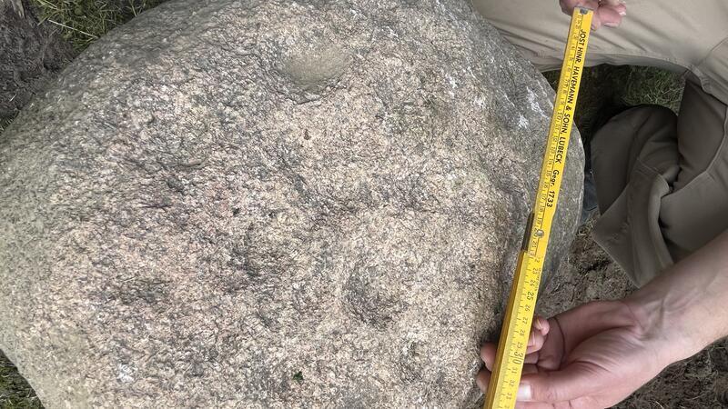 Überall sind kleine Schälchengruben auf dem 400 Kilogramm schweren Granitstein zu sehen.