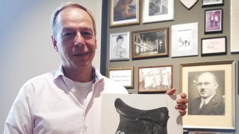Uli Lennartz vom Modehaus Peters. An der Wand hinter ihm hängt ein Bild des Geschäftsgründers Eugen Peters.