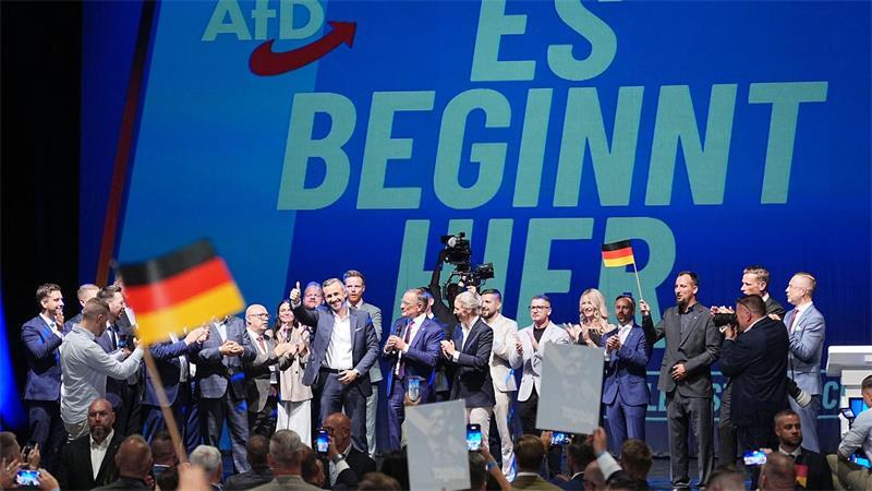 Ulrich Siegmund steht mit Funktionären der AfD bei der Wahlparty der AfD im Alten Theater in Magdeburg vor dem Schriftzug „Es beginnt hier“ auf der Bühne.
