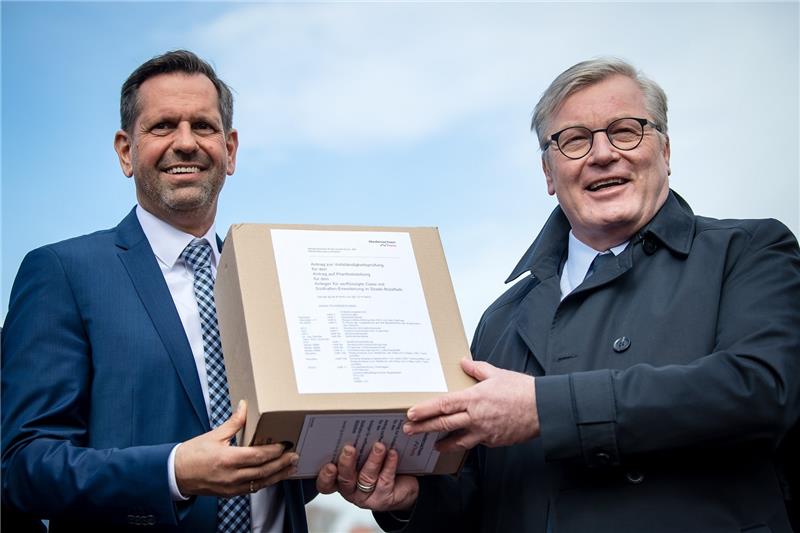 Umweltminister Olaf Lies (SPD; links) und Verkehrsminister Bernd Althusmann (CDU) in Stade mit einem Teil der Genehmigungsunterlagen für den Terminalbau. Foto: Sina Schuldt/dpa