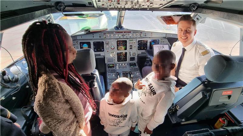 Die drei Adoptivkinder dürfen einen Blick ins Cockpit des Flugzeugs werfen, dessen Pilot sie nach Deutschland fliegt.