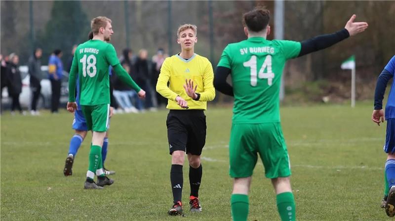 Schiedsrichter Calvin Meglin erklärt einem Spieler des SV Burweg etwas auf dem Spielfeld.