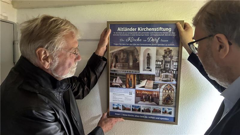 Kunst gegen Schließung: Cartoonist legt Kirche als Mahnung in Trümmern Unsere Kirche im Dorf lassen: Heinzfrieder Dürkes (von links) und Pastor Olaf Prigge hängen das neue Plakat der Altländer Kirchenstiftung auf.