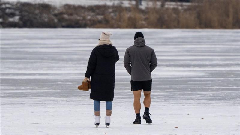 Unten kurz bei Minusgraden: Menschen laufen auf einem zugefrorenen See in Potsdam übers Eis.