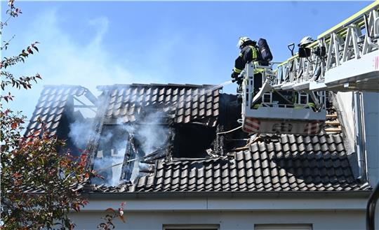 Unter Atemschutz bekämpfen Feuerwehrleute den Brand im Dachstuhl in Steinkirchen mit der Hilfe der Drehleiter aus Harsefeld. Im Inneren sind Löschtrupps im Einsatz, gemeinsam werden auf dem Dach des Hinterhauses die Pfannen entfernt. Fotos: