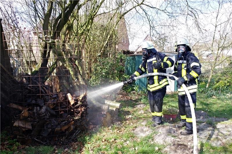 Unter schwerem Atemschutz löschen die Feuerwehrleute in Estorf einen Holzstapel, der durch Funkenflug in Brand geraten war. Foto: Hillyer-Funke