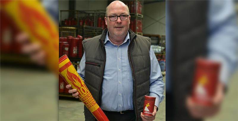 Unternehmer Gerhard Naujoks zeigt Löschmittel aus früheren Zeiten. Im Hintergrund stapeln sich die geleerten Feuerlöscher.