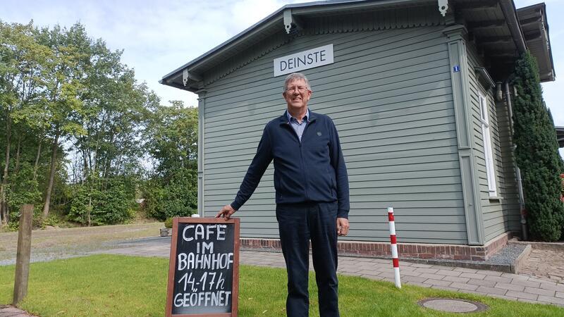 Deinster Café am Bahnhof wird schick gemacht Uwe Gooßen steht mit einem Schild, das für den Cafébetrieb wirbt, vor dem Deinster Bahnhof.