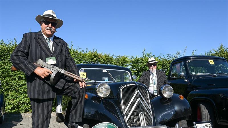 Verkleidete Teilnehmer stehen an einem alten Citroen Traction Avant bei einem Oldtimertreffen in Dessau. 