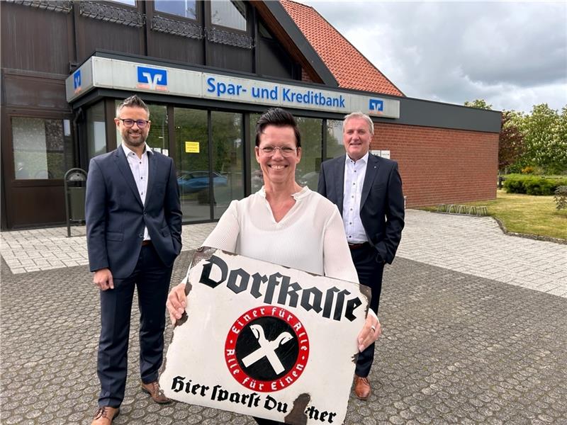 Verlässlichkeit steht für die Spar- und Kreditbank Hammah im 100. Jahr ganz oben, vor allem auch für die Vorstände Manuel Ropers (links) und Gerd Pott. Heike Bösch zeigt das Schild aus den Anfangsjahren. Das Motto „Dorfkasse, hier sparst Du