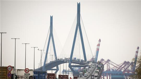 Verschiedene Fahrzeuge, LKW und Containertransporter fahren über die Köhlbrandbrücke im Hamburger Hafen. Die 1974 fertiggestellte und für den Hafen wichtige Brücke soll bis 2036 ersetzt werden.