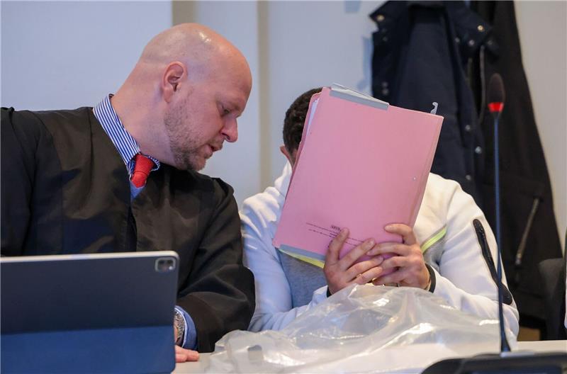 Verteidiger Phillip Kaiser (l) spricht beim Prozessauftakt mit einem der Angeklagten.